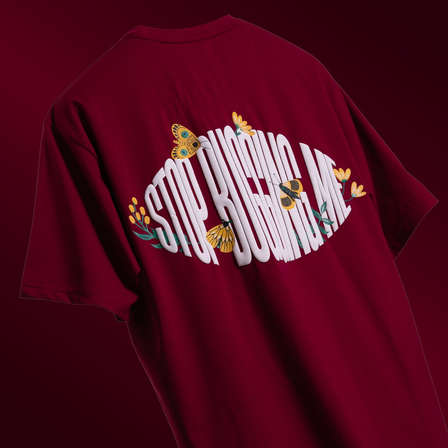 Bold maroon oversized 'Stop Bugging Me Tee' floating against a matching backdrop, featuring 'Cobalt Green' branding on the front. The back displays the playful 'STOP BUGGING ME' phrase with quirky bug graphics in screen and puff print. Made from 220 GSM cotton-rich fabric with bio-washed and gold-finished treatment for a soft, premium feel. The oversized, unisex design ensures comfort and style for all, perfect for casual wear with a sassy attitude.