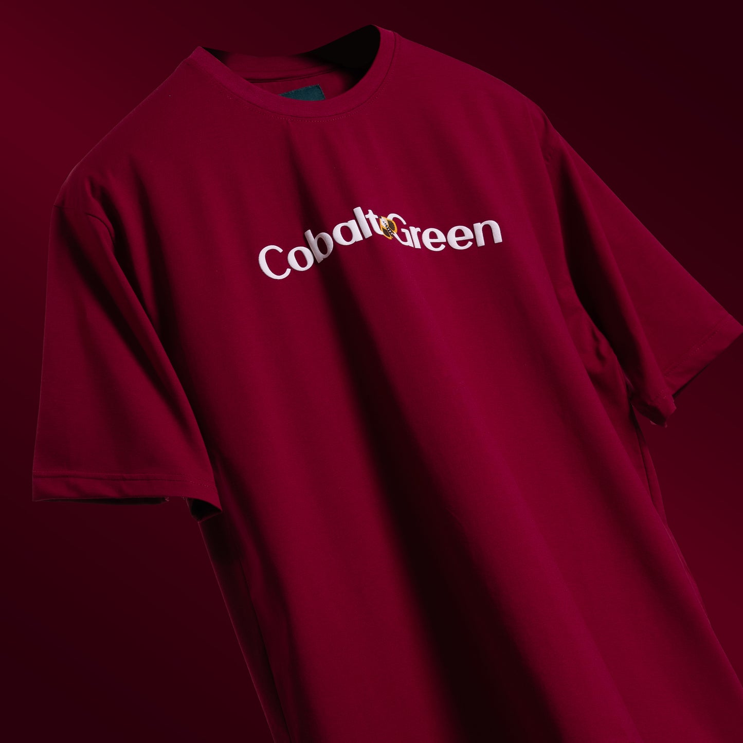 Bold maroon oversized 'Stop Bugging Me Tee' floating against a matching backdrop, featuring 'Cobalt Green' branding on the front. The back displays the playful 'STOP BUGGING ME' phrase with quirky bug graphics in screen and puff print. Made from 220 GSM cotton-rich fabric with bio-washed and gold-finished treatment for a soft, premium feel. The oversized, unisex design ensures comfort and style for all, perfect for casual wear with a sassy attitude.