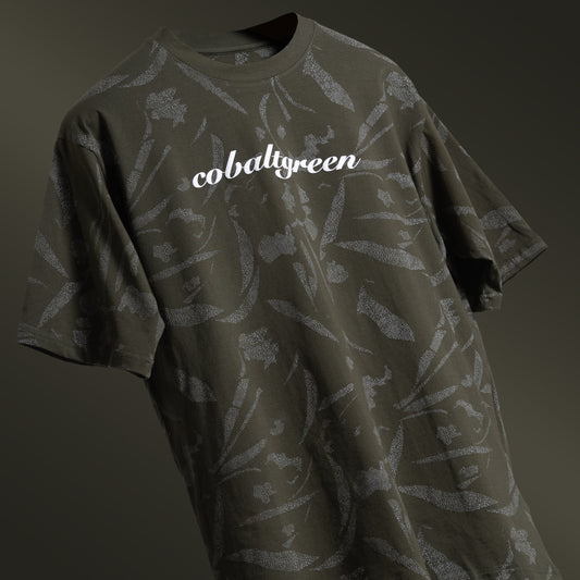 Olive oversized t-shirt with an all-over-print design, floating against a matching olive-toned background for a cohesive, monochromatic effect. The shirt is accented with 'Cobalt green' branding on the chest plate, offering a sleek and modern look.