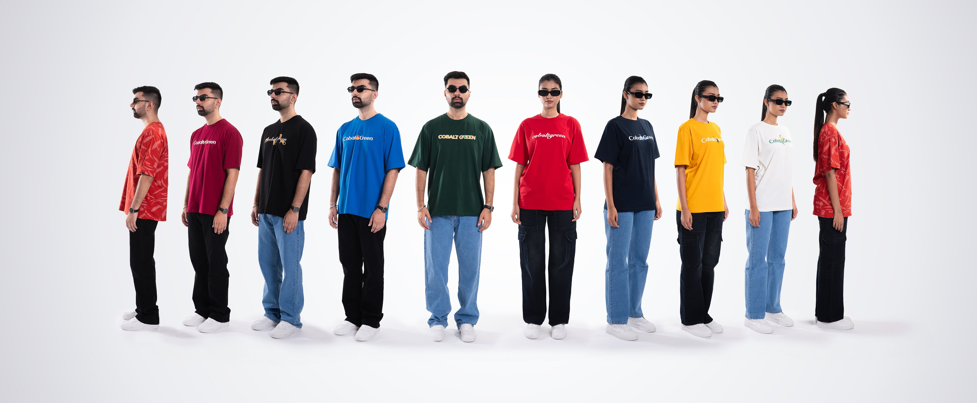 Image composition showcasing the entire Cobalt Green collection worn by both male and female models. The models, dressed in various oversized tees from the collection, pose confidently to highlight different designs, including bold graphic prints, floral accents, and unique phrases. Each tee is displayed in a relaxed, unisex fit, offering a perfect balance of style and comfort. The image captures the diversity and premium craftsmanship of the collection, making it an ideal representation of modern casual we