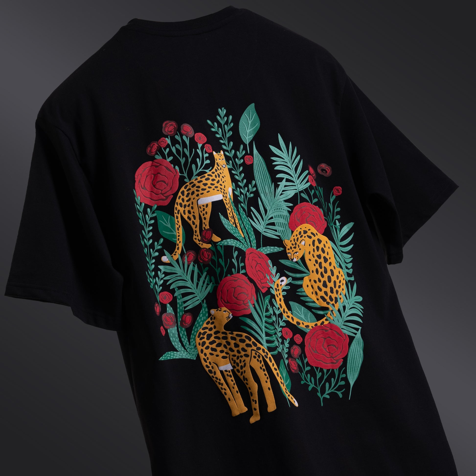 Classic black oversized 'Leopard Tee' floating against a matching backdrop, featuring a striking screen and puff print of a leopard and roses on both the front and back. The premium 220 GSM cotton-rich fabric ensures durability and comfort, while the bio-washed and gold-finished treatment provides a soft, luxurious feel. The relaxed, unisex fit offers a flattering look for all body types, making it the perfect choice for those seeking bold style with a touch of elegance.
