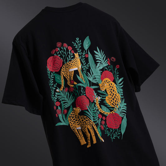 Classic black oversized 'Leopard Tee' floating against a matching backdrop, featuring a striking screen and puff print of a leopard and roses on both the front and back. The premium 220 GSM cotton-rich fabric ensures durability and comfort, while the bio-washed and gold-finished treatment provides a soft, luxurious feel. The relaxed, unisex fit offers a flattering look for all body types, making it the perfect choice for those seeking bold style with a touch of elegance.