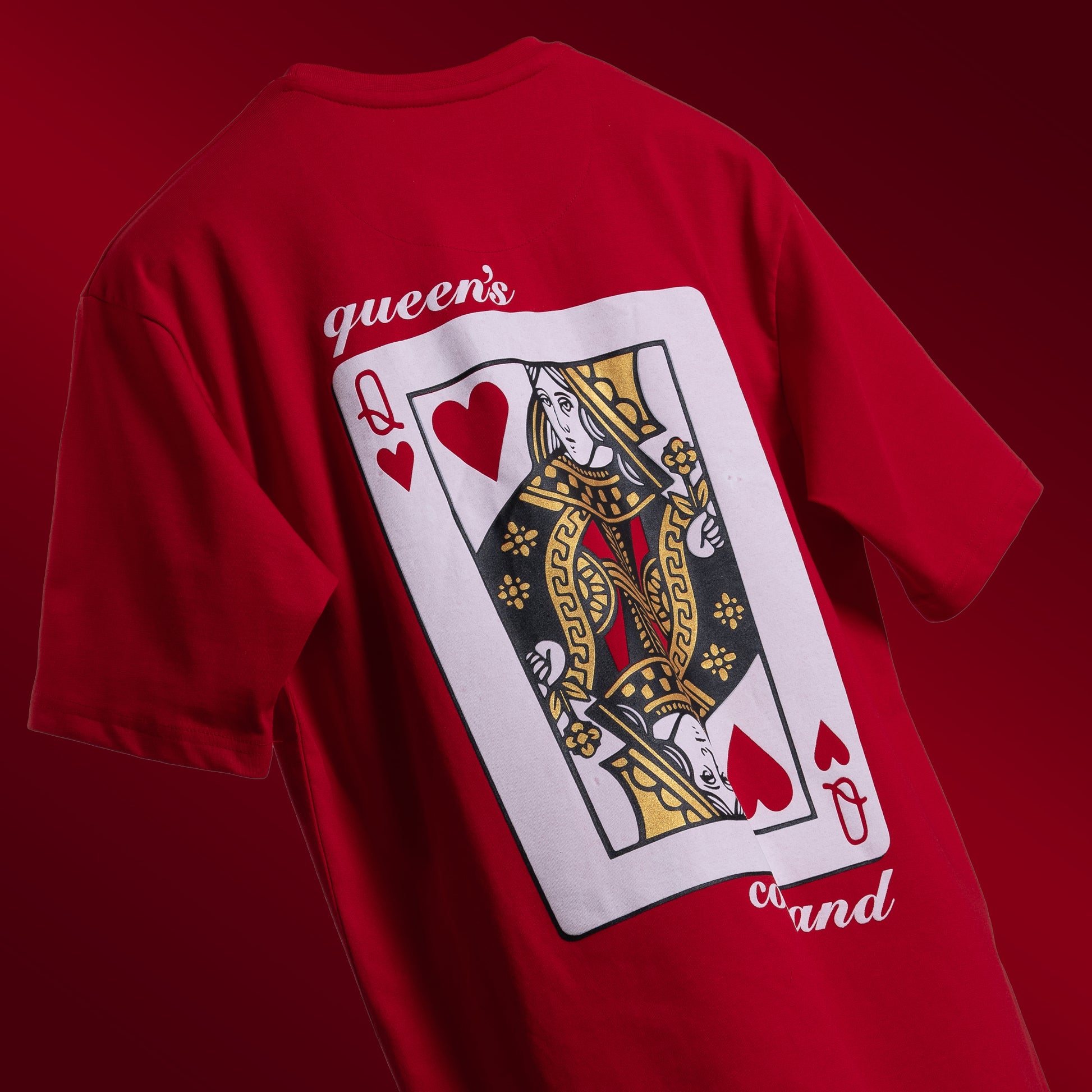 Striking red oversized 'Queen's Command Tee' floating against a matching backdrop, featuring 'Cobalt Green' branding on the front. The back showcases the bold 'Queen's Command' phrase with an intricately illustrated Queen of Hearts card in screen and puff print. Crafted from 220 GSM cotton-rich fabric with bio-washed and gold-finished treatment for a soft, premium feel. The oversized, unisex design offers a relaxed, flattering fit, perfect for expressing confidence and royal style.