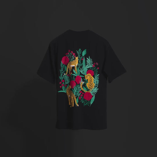 Video showcasing the back of the classic black 'Leopard Tee' floating against a matching backdrop. Text overlays highlight key features: bold screen and puff print of a leopard and roses, premium 220 GSM cotton-rich fabric, and bio-washed and gold-finished treatment for a soft, luxurious feel. The video emphasizes the oversized, unisex fit and wild, yet elegant design, perfect for effortless style and comfort.