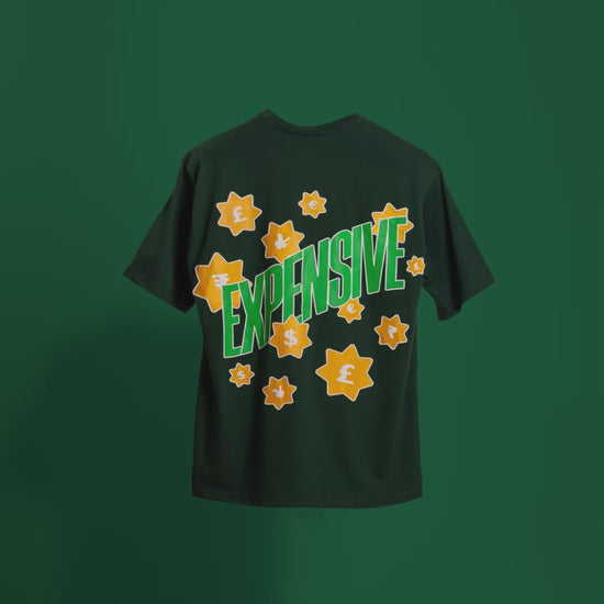 Video showcasing the back of the deep dark green 'Expensive Tee' floating against a matching backdrop. The screen and puff print design of the word 'Expensive' with currency symbols is prominently displayed, emphasizing the luxurious, bold style of the oversized tee.